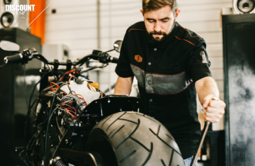 Repair man fixes motorcycle for customer with extended service plan